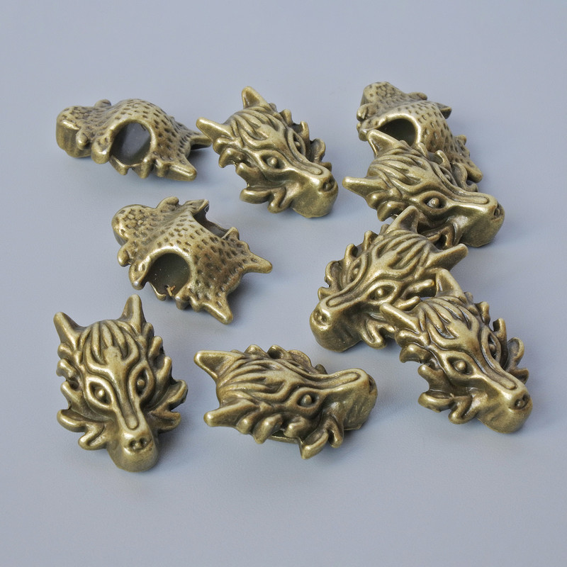Koralik-wkładka „Smok”, wymiary 18×13×8 mm, średnica otworu 3,7 mm, opakowanie 9 szt. ±, kolor metalu brązowy