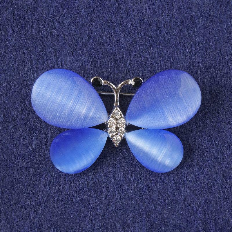 Broszka Motyl z niebieskim kocim okiem, białymi kryształkami, metal srebrzysty 25×38 mm+
