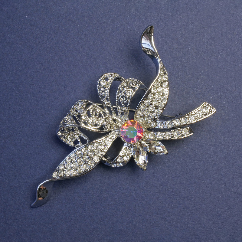 Broszka Akcent z tęczowym kryształem i białymi cyrkoniami, metal srebrzysty 78×41 mm +