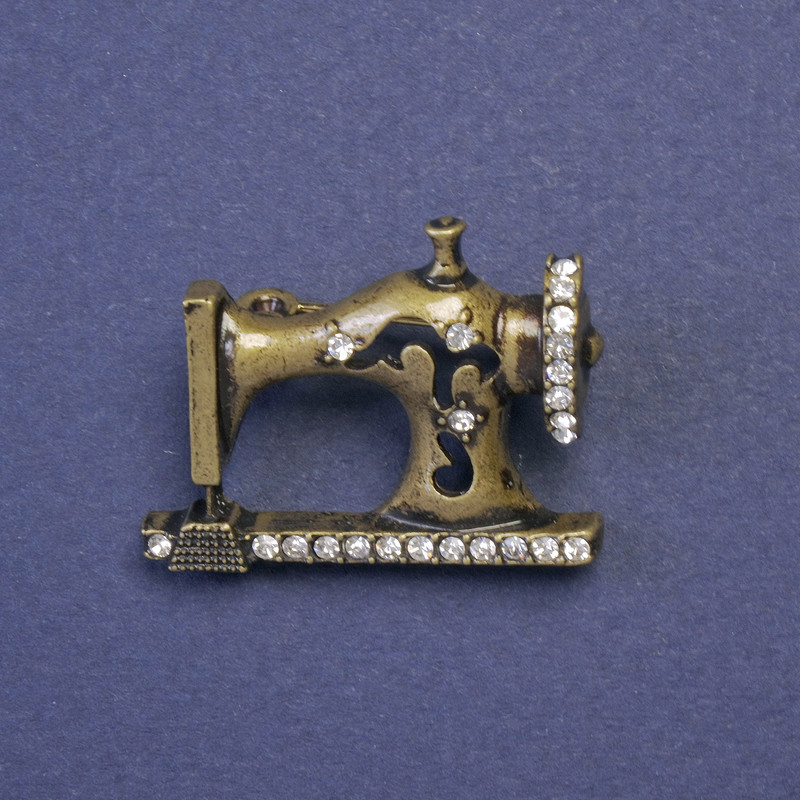 Broszka w formie maszyny do szycia z białymi kryształami, kolor metalu 'stare złoto', 21×29 mm