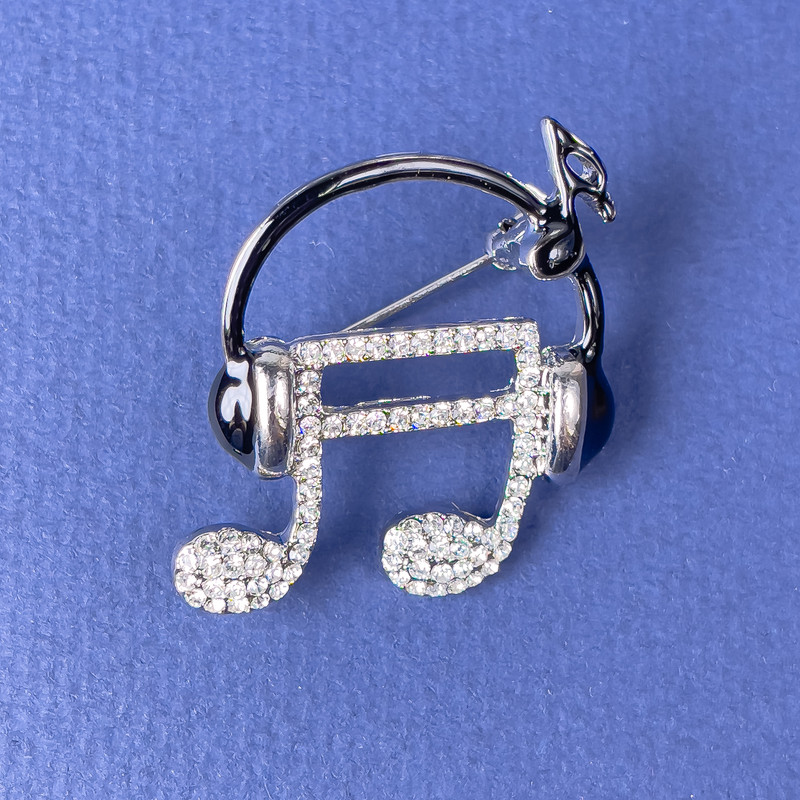 Broszka «Nuta w słuchawkach», białe kryształy, czarna emalia, srebrzysty metal, 27×32 mm+