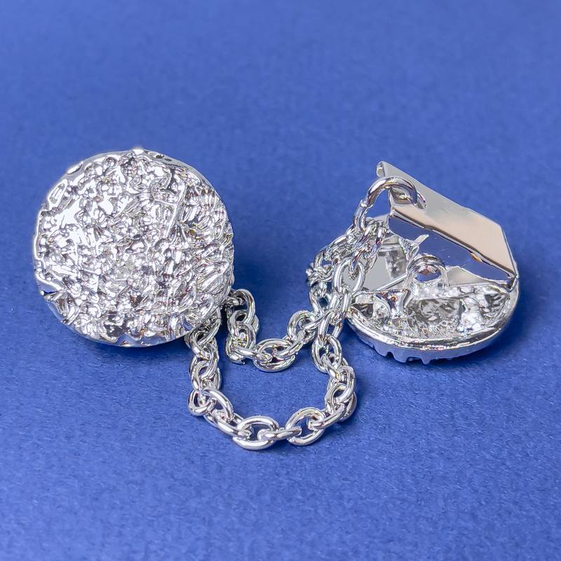 Broszka do kardiganów ze srebrzystego metalu, średnica ok. 20 mm, łańcuszek długości 9 cm