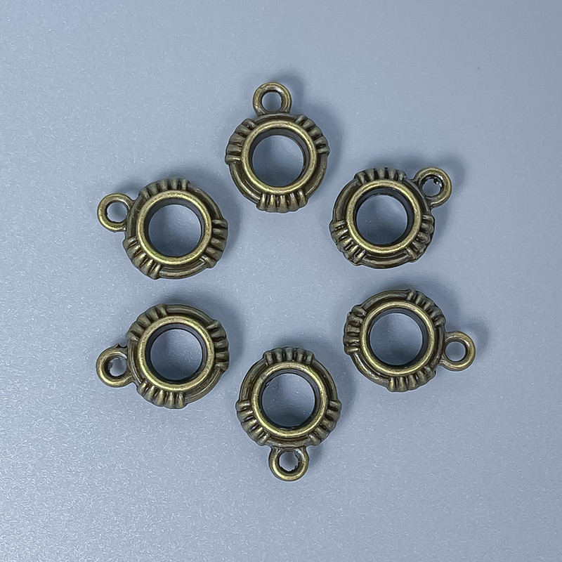 Zawieszka typu bail w kolorze brązu, wymiary 13×10×4 mm, otwory 5 mm i 1,5 mm, opakowanie 18 szt.
