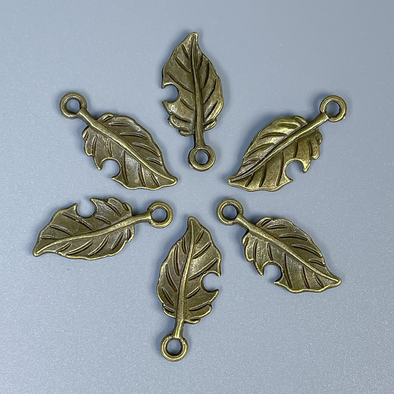 Zawieszka Liść w kolorze antycznego brązu, wymiary 23×10×1 mm, otwór 2 mm, opakowanie 20 g (~26 szt.)