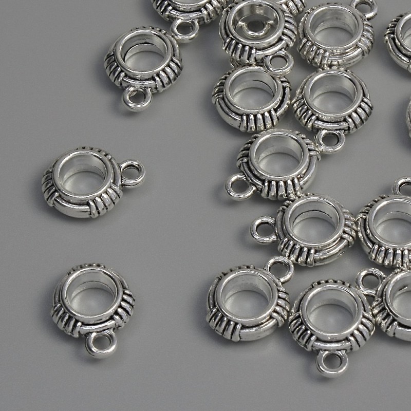 Zawieszka bail, kolor metalu: srebro, wymiary 13×10×4 mm ±, otwory o średnicy 5 mm ± i 1,8 mm ±, opakowanie 18 szt.