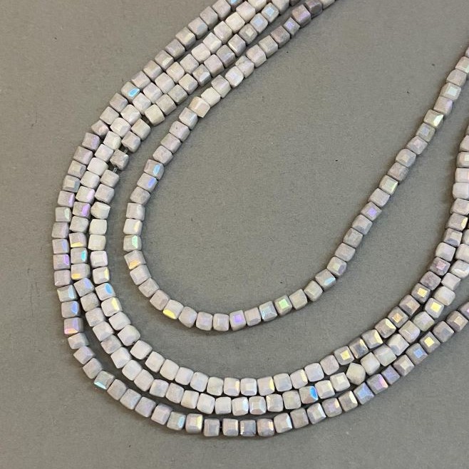 Koraliki czeskiego kryształu szare z powłoką benzynową na nici, kostki fasetowane o wymiarach 4×4 mm, długość 38 cm