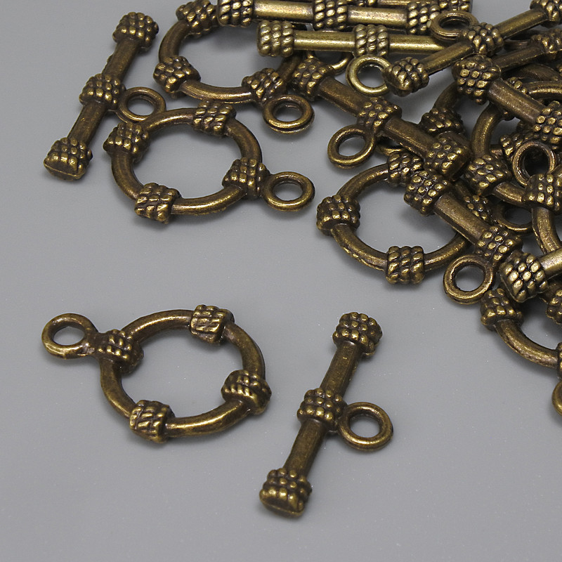 Zapięcie toggle, wymiary: 19,5×3,5 mm; koło o średnicy około 14 mm; średnica otworu 9 mm; kolor metalu: brąz patynowany; 11 szt.