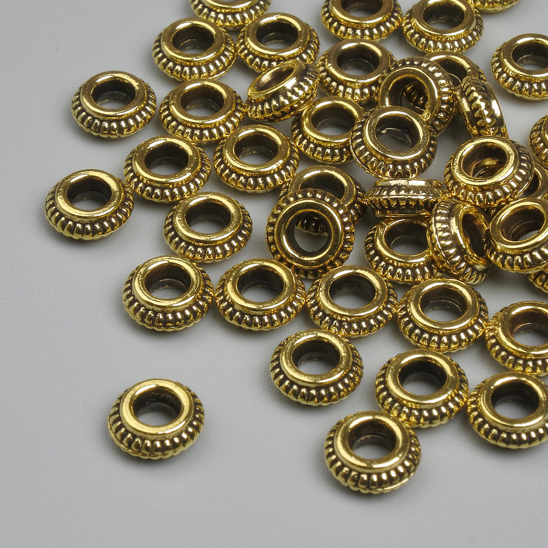 Koralik-wstawka w kolorze złotym, średnica 7×3 mm, otwór ok. 3 mm, opakowanie ~39 szt.
