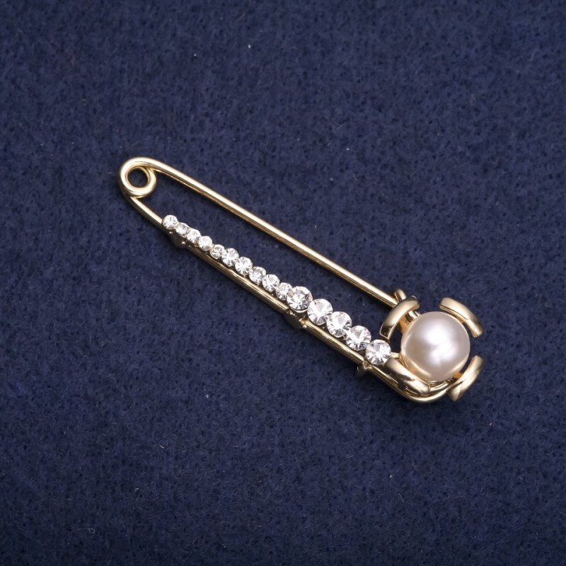 Broszka–spinka z białymi kryształkami i białą perłą, 60×15 mm, metal w kolorze złotym