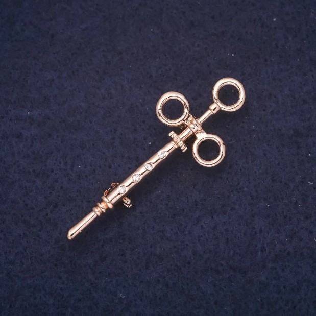 Broszka w formie strzykawki ze kryształami, metal w kolorze złotym, 17×45 mm