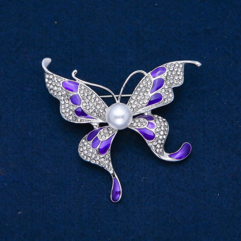Broszka Motyl z białymi kryształami, emalią, koralikiem, metalem srebrzystym 60×60 mm +