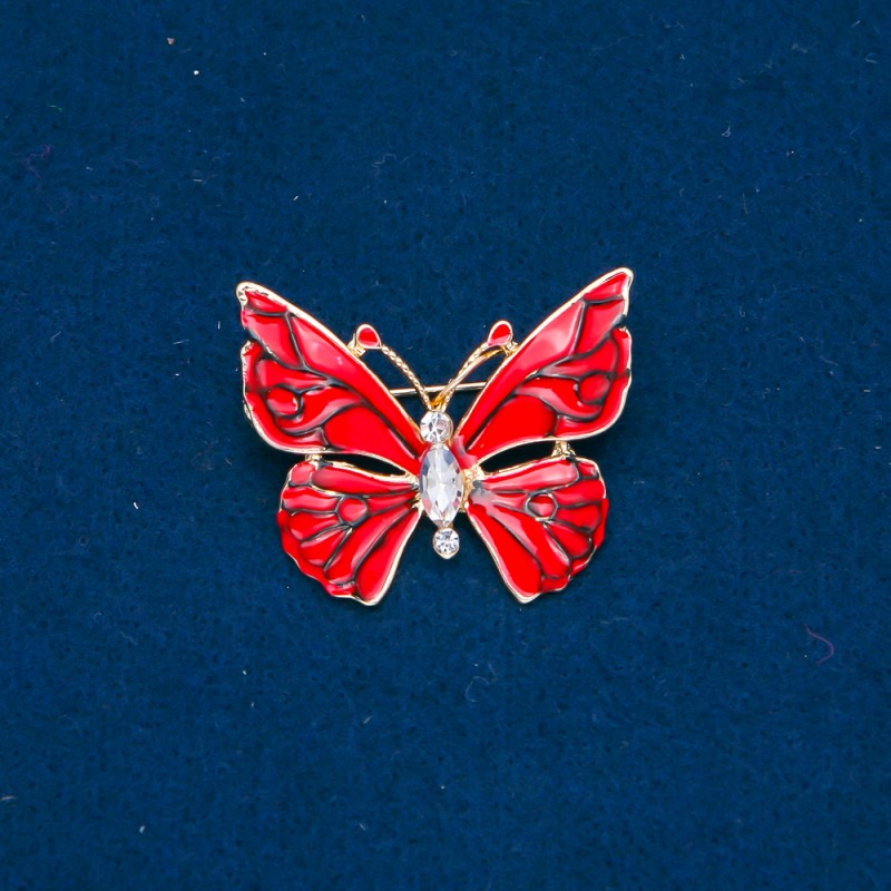 Broszka Motyl z złocistym metalem, czerwoną emalią i białymi kryształami 32×37 mm +