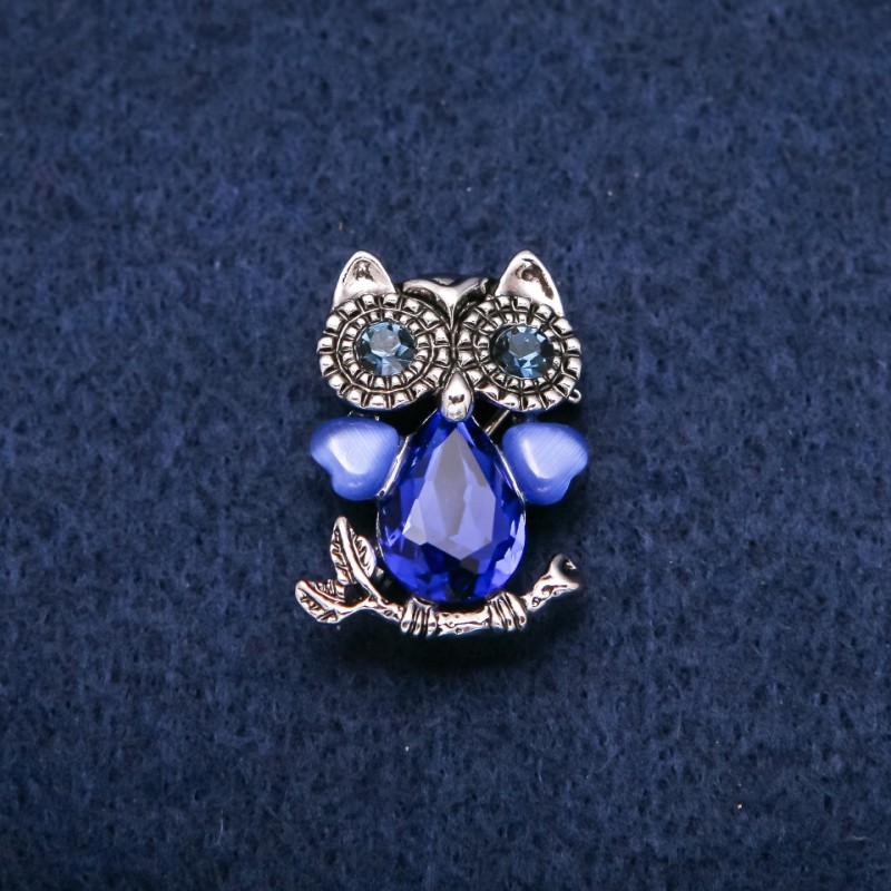 Broszka Sowa z kamieniem typu kocie oko i niebieskimi kryształami ze srebrzystego metalu 19×28 mm