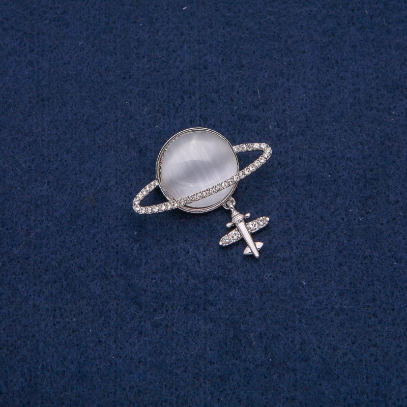 Broszka Saturn Kocie oko z samolotem, srebrzysty metal z białymi kryształami 35×20 mm +