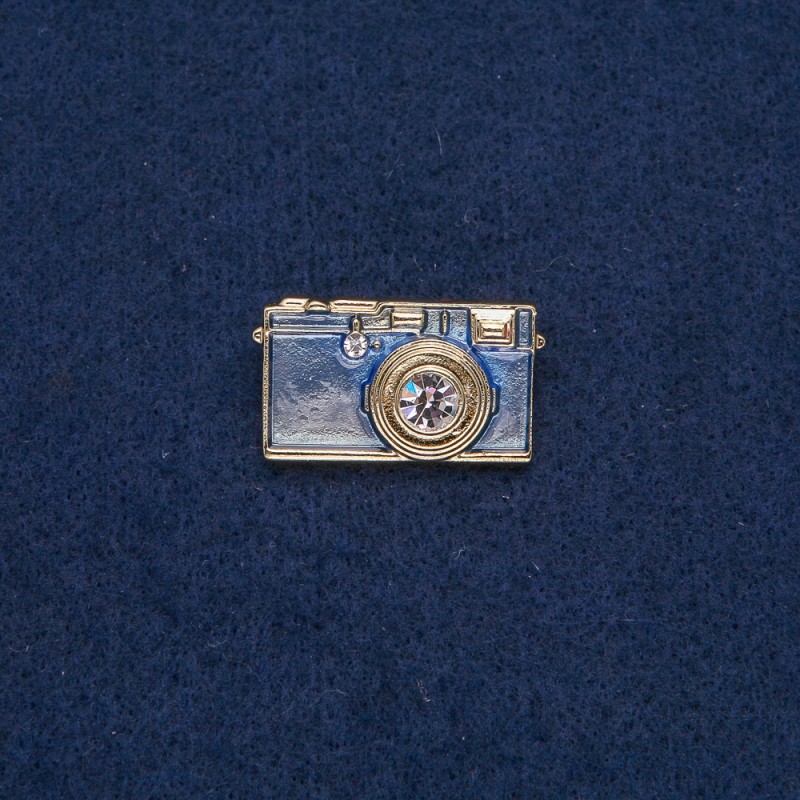 Broszka w kształcie aparatu fotograficznego, złocisty metal z błękitną emalią i białymi kamieniami 30×17 mm +