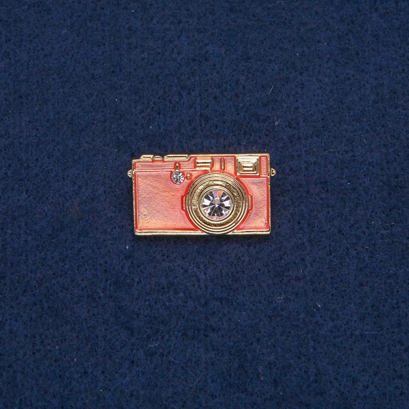 Broszka «Aparat fotograficzny» ze złocistym metalem, różową emalią i białymi kamieniami 30×17 mm +