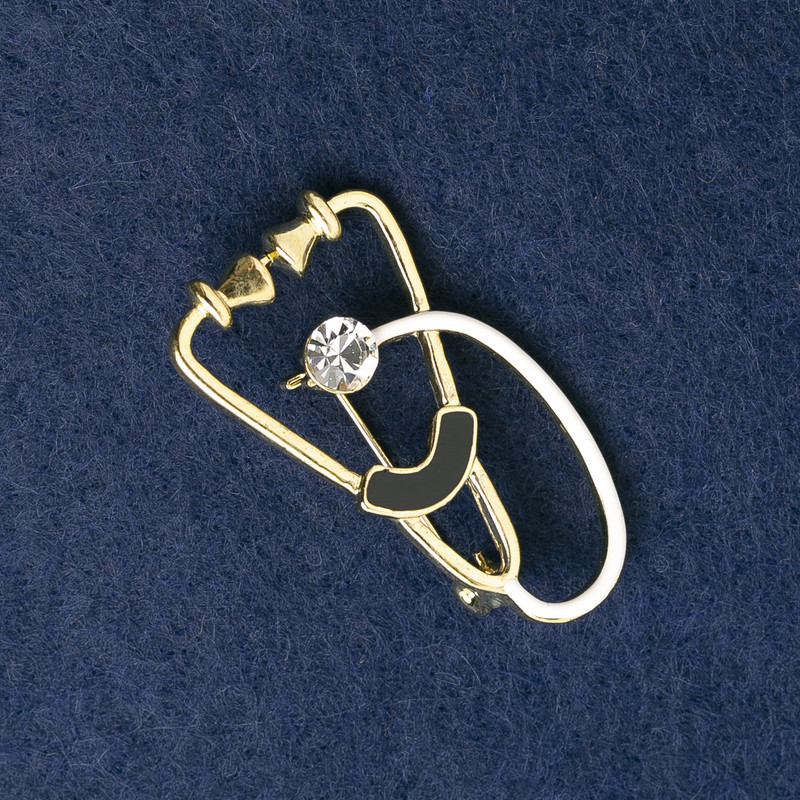 Broszka ze stetoskopem, emaliowana na biało i czarno, z białym kamieniem, metal złocisty 43×24 mm