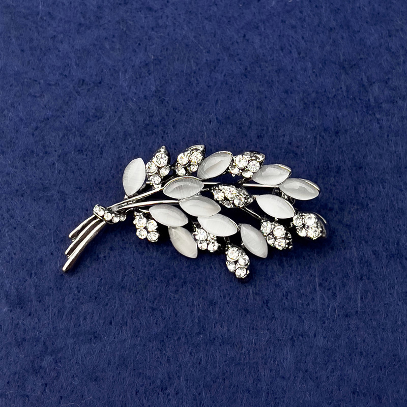 Broszka Gałązka z białym kocim okiem, białe kryształy, metal srebrny, średnica 50×27 mm