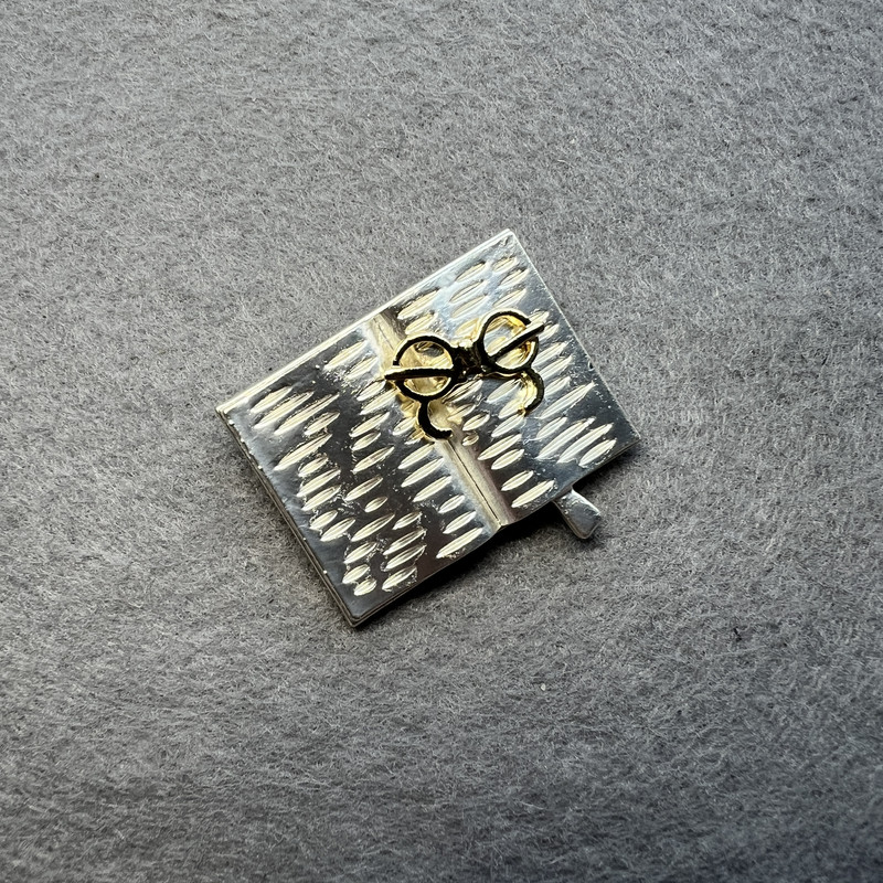 Broszka Książka z okularami, jasnoszara i złocista emalia, srebrzysty metal 35×26 mm