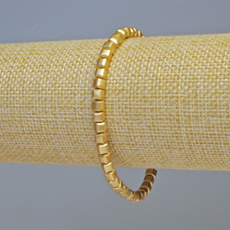Bransoletka z hematitu w kształcie kostek o kolorze matowego złota, o wymiarach około 4×4 mm, długość 18 cm, elastyczna