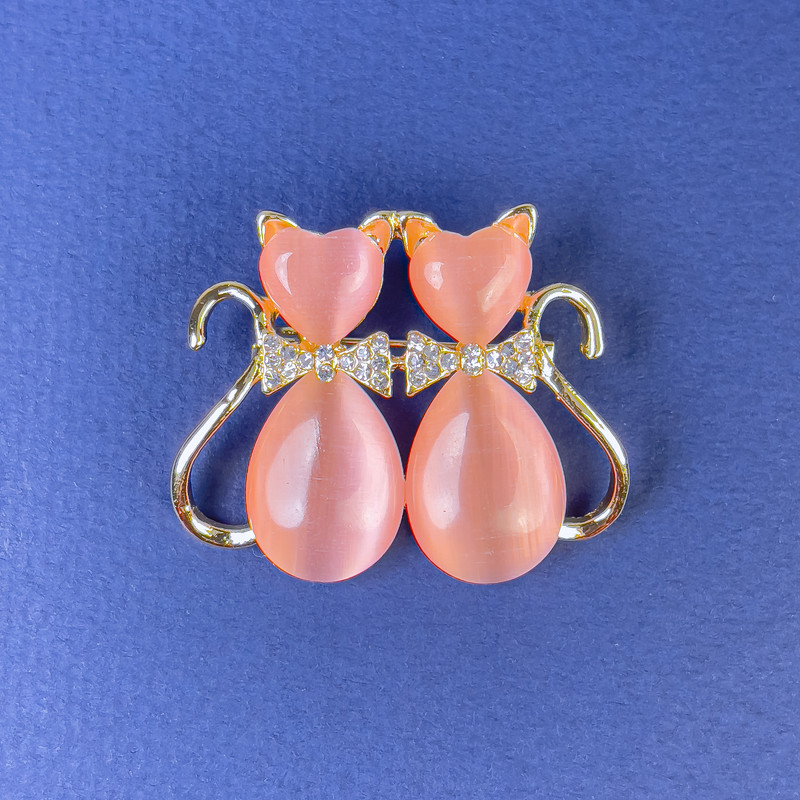 Broszka „Koty” z różowym kamieniem Kocie Oko, białymi kryształami, metal złocisty, średnica 31×38 mm +