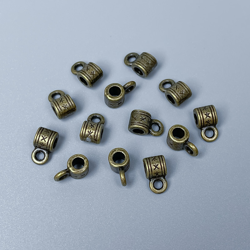 Zawieszka typu bail, kolor metalu: brązowy, rozmiary 9×5×5 mm ±, otwory Ø 2,5 mm ±, Ø 2 mm ±, opakowanie 34 szt.