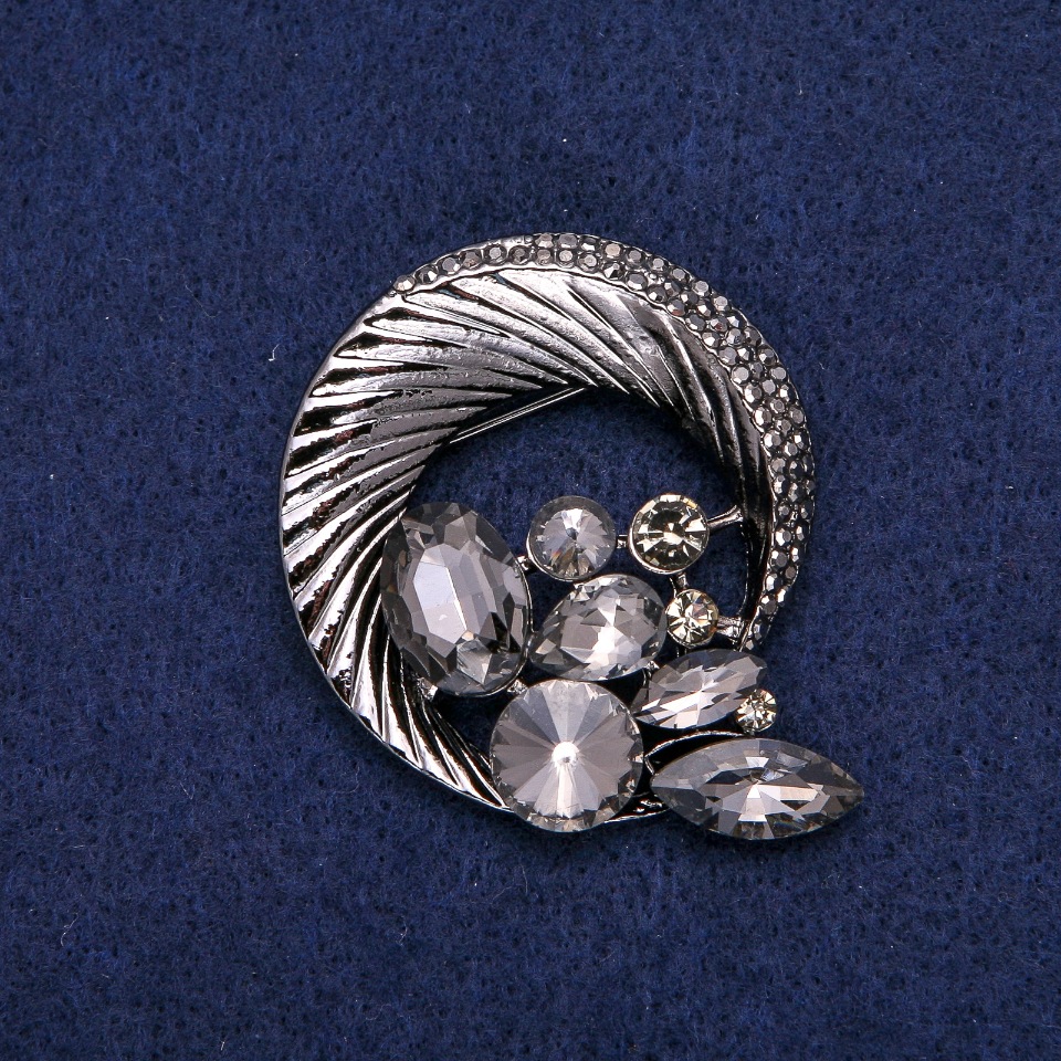 Broszka okrągła z obwódką z cyrkoniami, splatająca się w piękną kompozycję, ciemny metal 45×50 mm