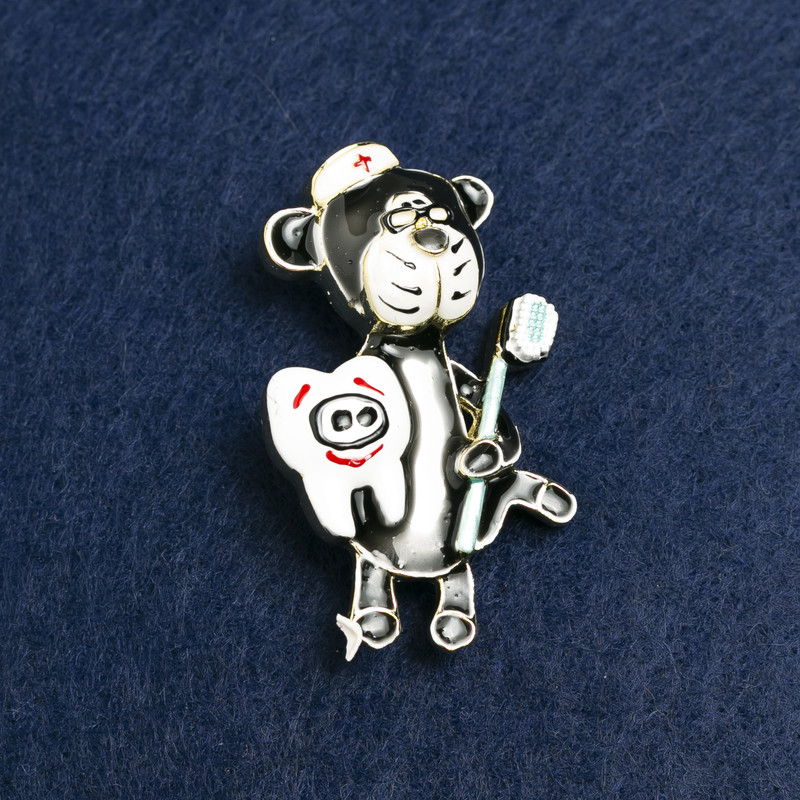 Broszka Niedźwiedź Stomatolog – złocisty metal i emalia 50×30 mm +